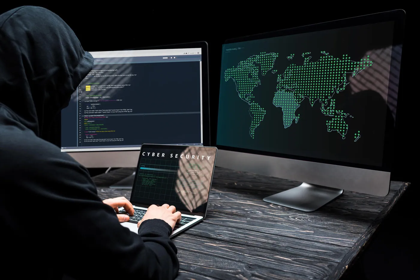 A cybersecurity specialist working at two monitors showing a world map and network traffic analysis